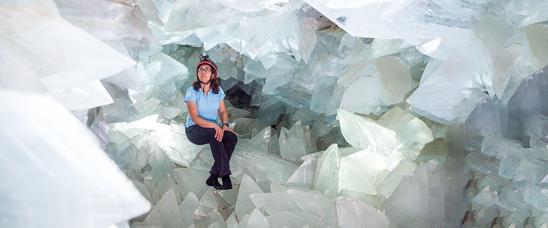 A girl wearing a helmet sitting surrounded by walls of crystals